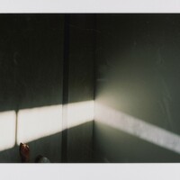 Framed photograph of a hand reaching into a beam of light. The shadows are dark at the top, gradually becoming lighter. 